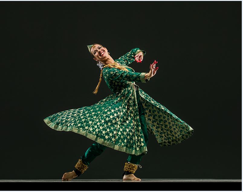 Charlotte Moraga dancing in a swirling green and gold dress