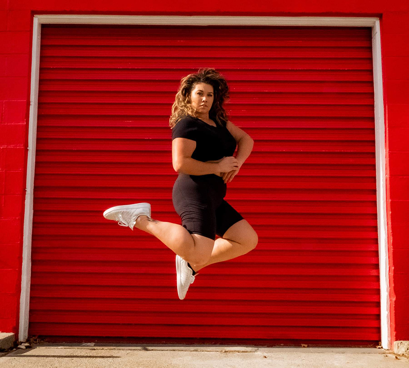 Amy jumping in front of a red garage.