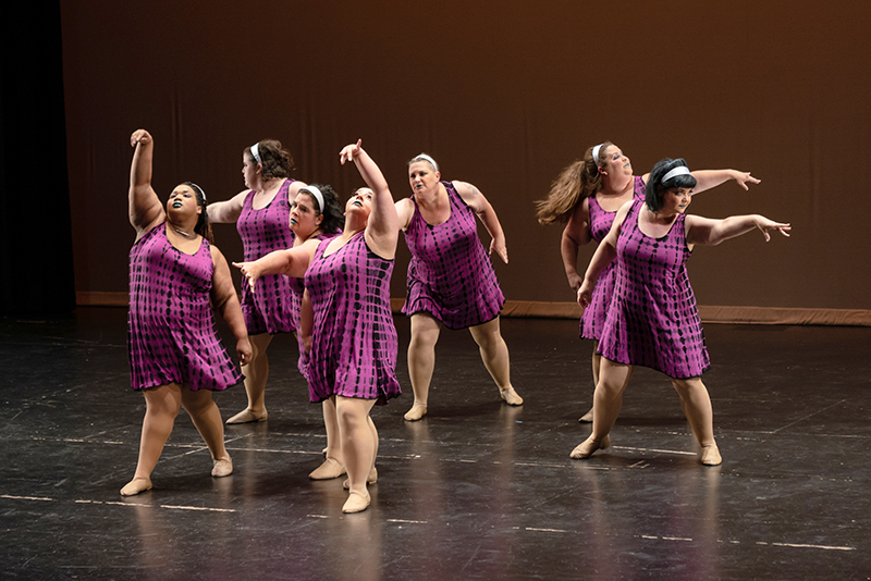 Seven dancers in a clump onstage making various shapes