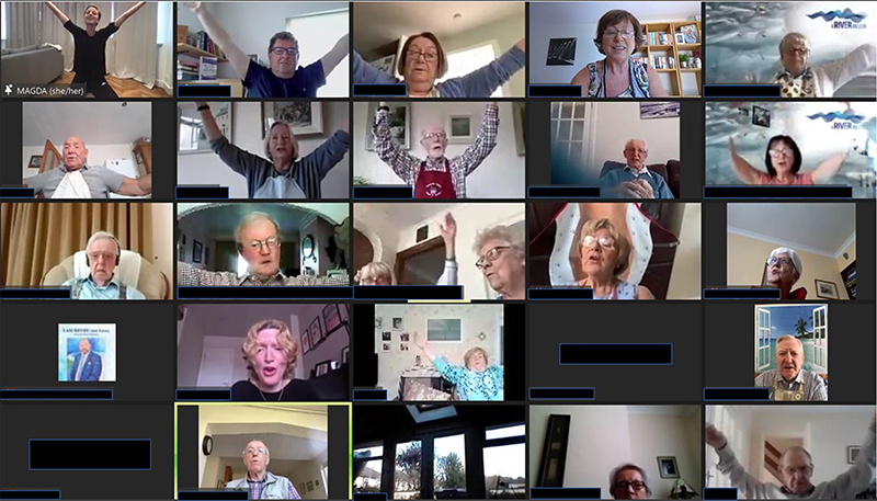 A Zoom screenshot with about 20 squares filled with people raising their arms ina V-shape.