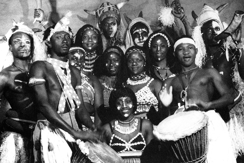 Dancers in Senegalese costumes gather together and smile.