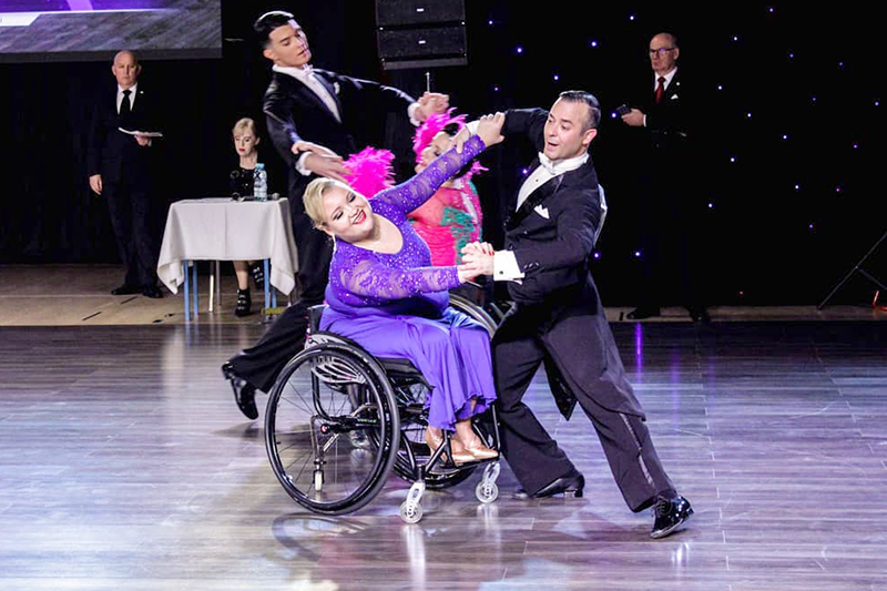  Nastija in a purple dress and her partner in a black suit in competition