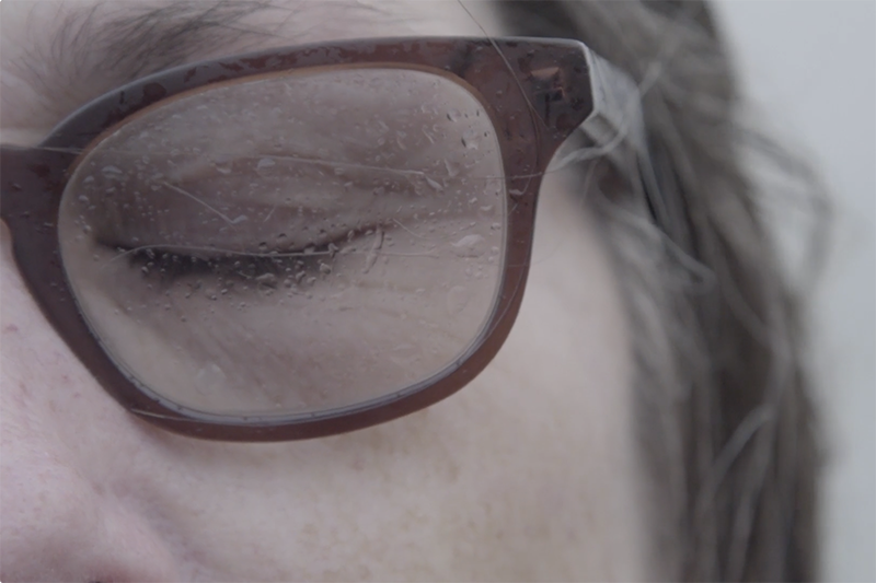 A closeup of a woman wearing glasses with her eyes closed.