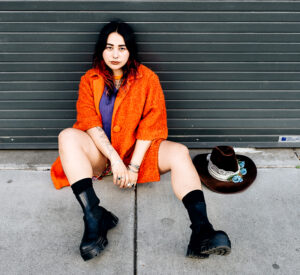 Fanny Kahlo sitting against a garage