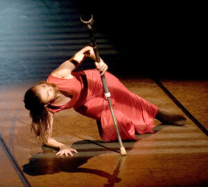 Nadia Adame in red dress leaning low over her crutches