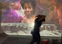 Danielle dancing with her face projected on the wall behind her