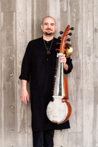 Alam Khan standing and holding his sarod