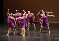 Seven dancers in a clump onstage making various shapes