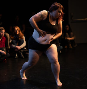 KT in performance grabbing her belly.