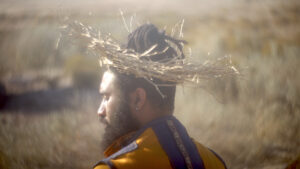 A closeup of Miles' head from behind. He is in the desert and wearing a straw hat.