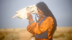 Nikesha holds an animal skull to her forehead.