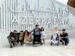 Dancers with and without disabilities posing in front of a sign that says "Azerbaijan."