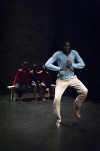 Momar dancing with arms and knees to the sides.