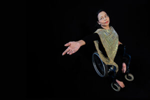 Lusi reaches sideways with uplifted hand.