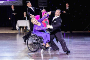 Nastija in a purple dress and her partner in a black suit in competition