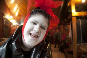 Isabel smiles into the camera with a white painted face and red bow in her hair.