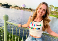 Alexandra standing and smiling at the riverfront wearing a shirt that says, "It's time to dance."