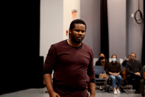 Dominic walks forward in performance with the audience behind watching him.