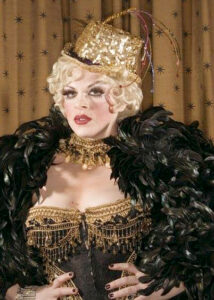 Dr. Lucky with hands on her hips wearing a gold and black burlesque costume.