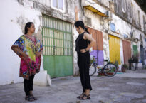 Two women stand in front of a building facade trying flamenco postures