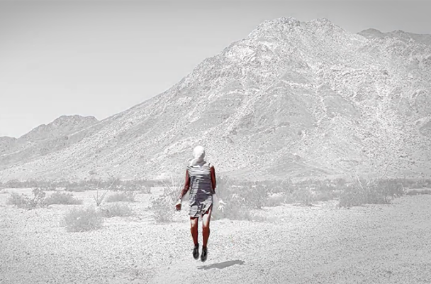 An image of a person walking in a barren Southwest landscape.
