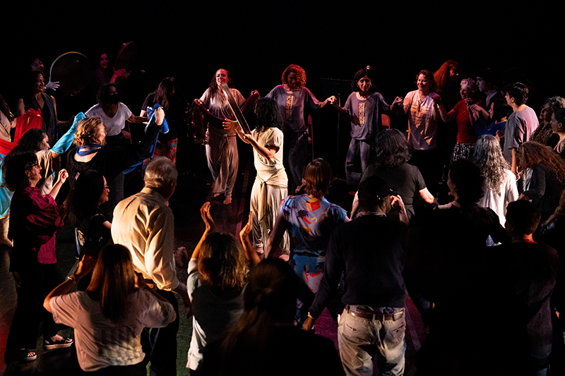 Many people dancing onstage in a circle together.
