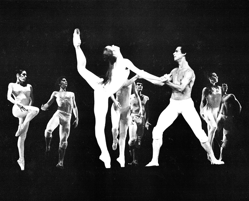 An old photo of a pas de deux with the woman in an extreme arabesque and the man holding her hands in fourth position.