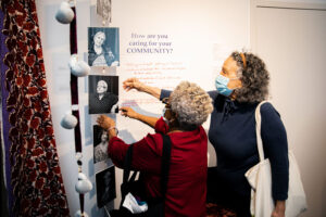 Two people look at and point to a wall exhibit.
