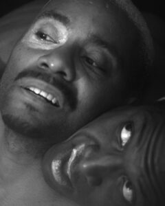 One dancer puts their chin in the other dancers neck and looks up at them. The other dancer looks away. The image is in black and white.