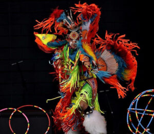 A hoop dancers wearing flowing regalia with hoops around his legs.