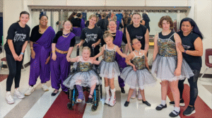 A group of people, some in costumes and some in wheelchairs, pose and smile at the camera.