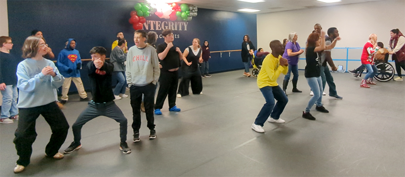 A large group of people take a dance in a dance studio. 