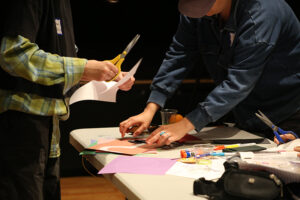 Hands cutting a pasting paper on a table.