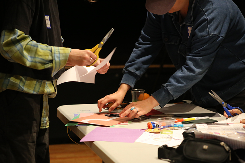 Hands cutting a pasting paper on a table.
