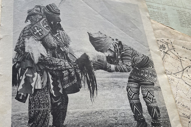 low res (3).jpg You said: one sentence image description Copilot said: Copilot A black-and-white printed photograph shows a costumed ceremonial figure wearing a horned mask, layered patterned garments, and long fabric-covered arms, with a caption below reading “Ezenwanyi (Maiden mask), She is the Queen of Ekwuru.” low res (2).jpg You said: one sentence image description Copilot said: Copilot A black-and-white printed photograph shows a masquerade figure completely covered in long raffia fibers holding a staff, with a caption identifying the figure as “Akpuọokiekapụala (Ọkakpọ),” responsible for the inspection of roads. low res (1).JPG You said: one sentence image description Copilot said: Copilot A black-and-white printed photograph shows two elaborately costumed masquerade figures standing outdoors, with one figure bowing toward the other while both wear heavily patterned garments and layered ceremonial adornments, accompanied by a caption identifying them as Ezemuọ and Adamma masquerades.